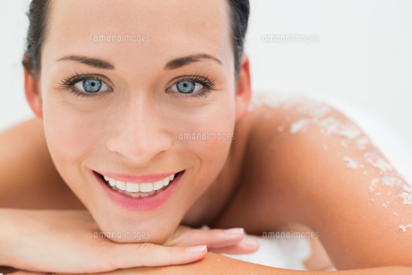 Peaceful brunette lying with salt scrub on back smiling at camera FYI00002442 Peaceful brunette lying with salt scrub on back smiling at camera FYI00002442