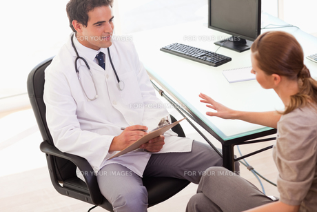 Doctor writing down the symptoms his patient is describing FYI00484810 Doctor writing down the symptoms his patient is describing FYI00484810